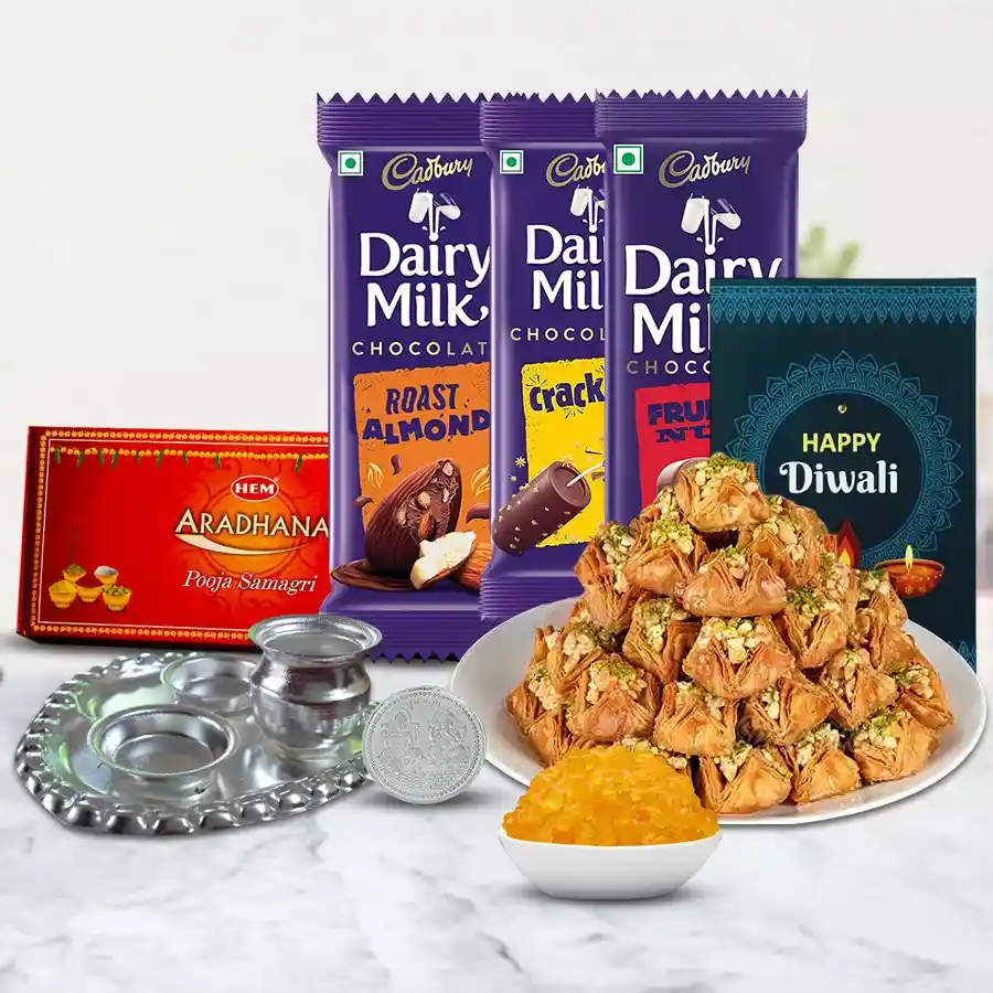 Pyramid Baklava Magic Box with Cadbury Mantra featuring Baklava, Cadbury Dairy Milk bars, silver pooja thali, Ganesh Laxmi coin, Kesaria Misri, pooja samagri, and a Diwali card.