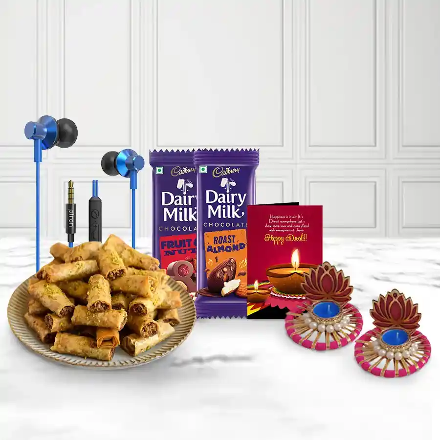 A festive basket containing Roll Baklava, Cadbury Fruit & Nut and Roast Almond bars, Ptron Earphones, two Lotus Tea Light Candle Holders, and a Diwali card.