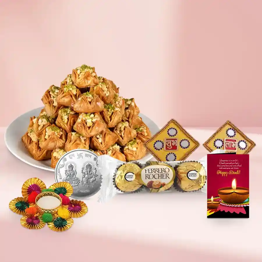 Gift basket containing Pyramid Baklava, three Rocher chocolates, a silver-plated Ganesh Laxmi coin, a Shubh Labh wall sticker, a tea light candle holder, and a Diwali card, all arranged decoratively for the festive season.