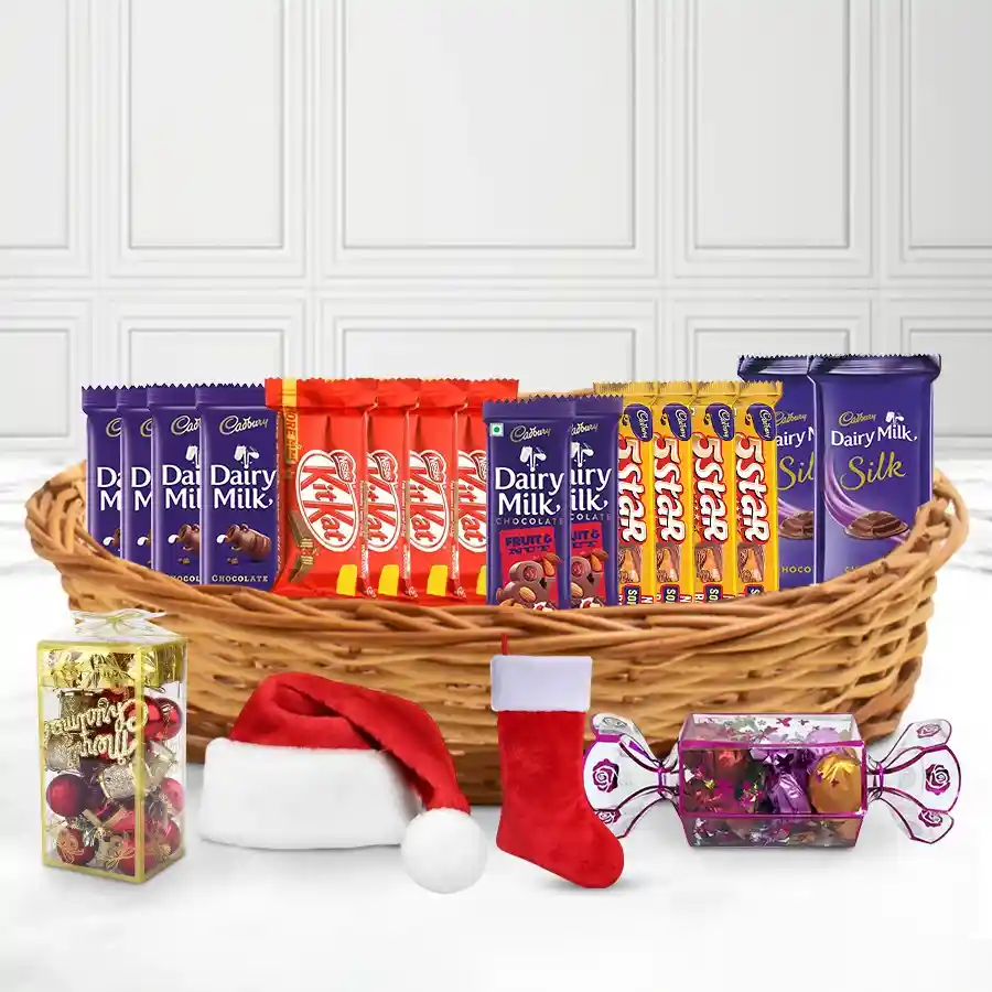 X-Mas Miracle Chocolate Treat Basket filled with Cadbury Dairy Milk, Nestle Kit Kat, 5-Star bars, Dairy Milk Silk, and Fruit & Nut chocolates, decorated with Christmas ornaments and a Santa Claus cap