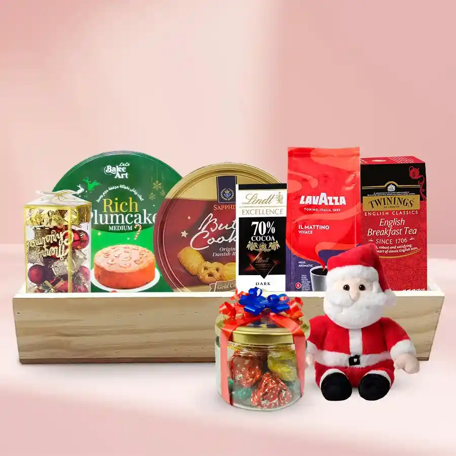Gift tray filled with Christmas treats including fruit cake, Danish cookies, English breakfast tea, Lavazza coffee, Lindt dark chocolate, and handmade chocolates, decorated with festive ornaments on a wooden tray.