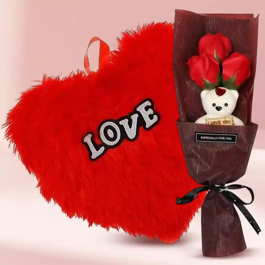 Gorgeous artificial red roses with a teddy bear and a red heart-shaped cushion arranged in a bouquet.