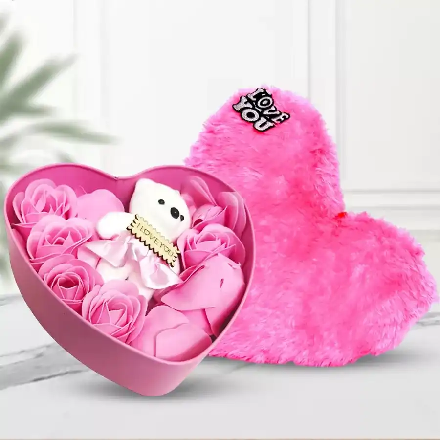 Romantic Rose Day gift trio featuring fresh roses in a heart-shaped box, a cuddly teddy bear, a glowing LED jar, a musical card, and a soft pink heart cushion.