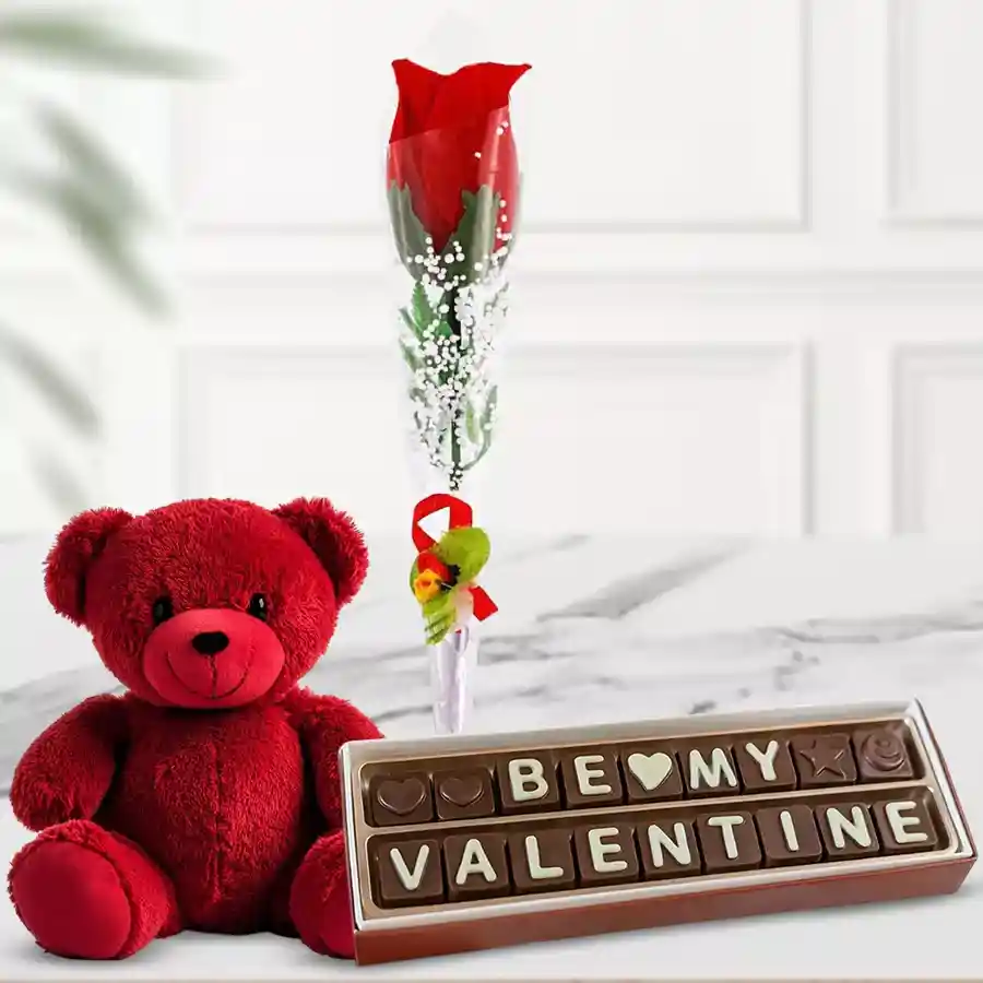 Red rose stick, red teddy bear, and handmade chocolates arranged together as a Valentine's gift.