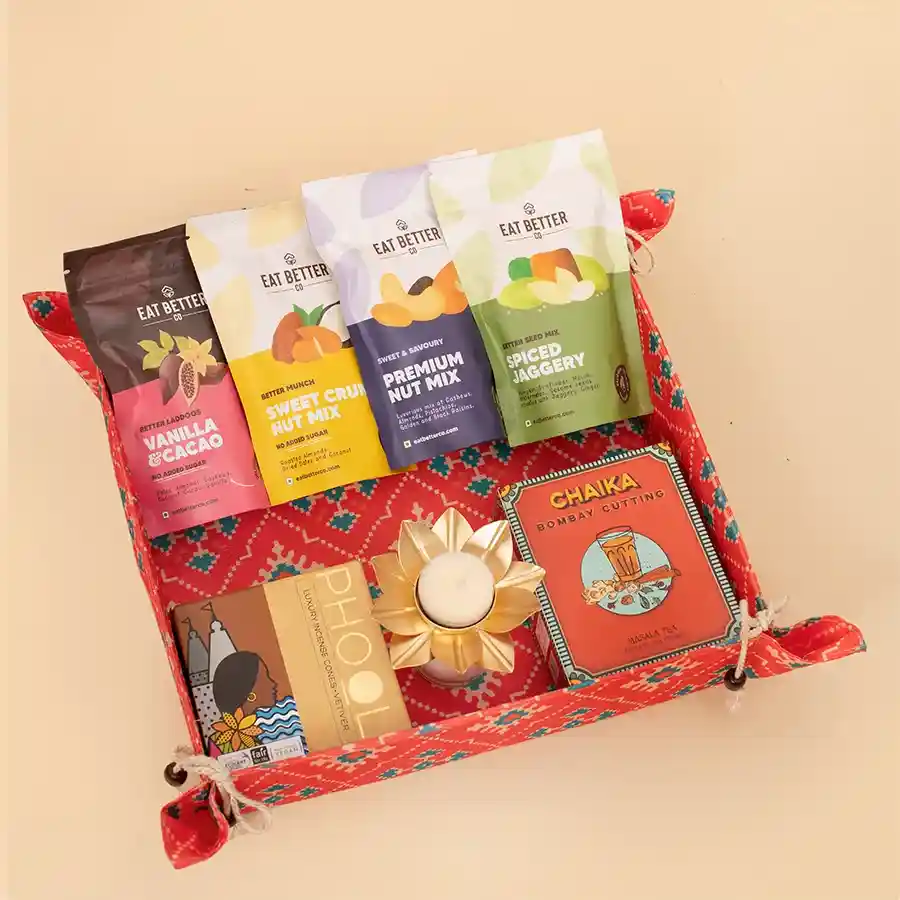 Marvelous Patola Art Decorative Tray Gift Hamper filled with premium nut mixes, vegan vanilla & cacao laddoos, spiced super seeds, gourmet raisins, blooming rose black tea, natural incense cones, and a plantable seed ball in a reusable Patola fabric tie-up tray.