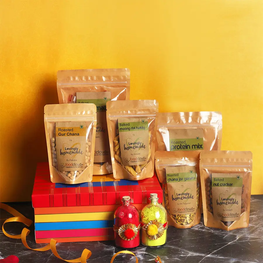 A vibrant gift hamper featuring organic gulal and an assortment of tasty snacks for Holi celebration.