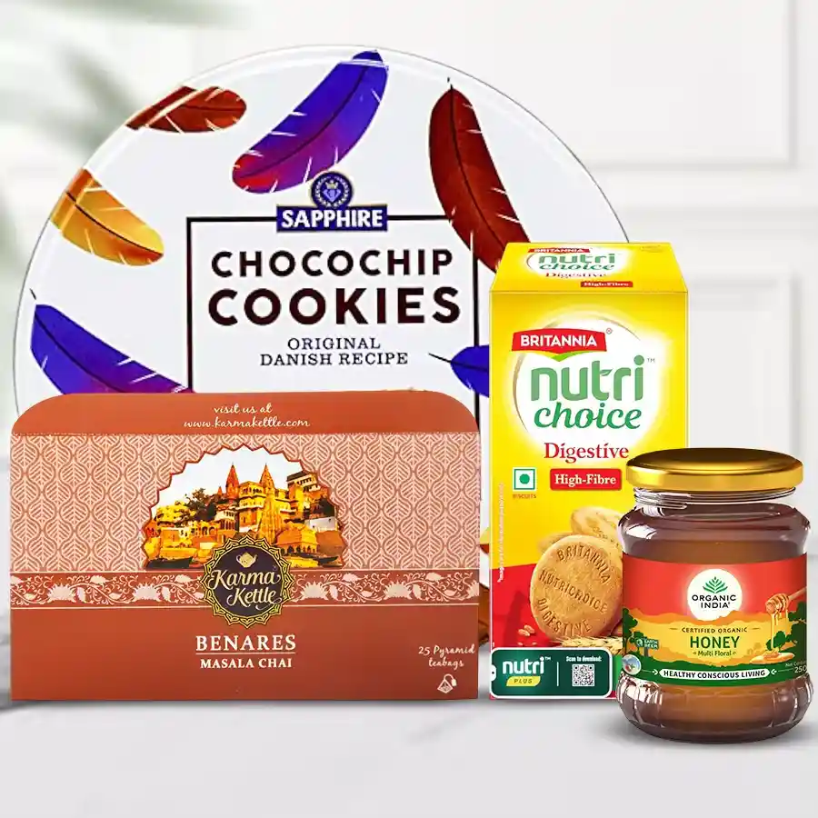 Delicious Snacks with Olives N Cutting Masala Chai Hamper featuring chai, cookies, biscuits, and honey arranged on a decorative background.