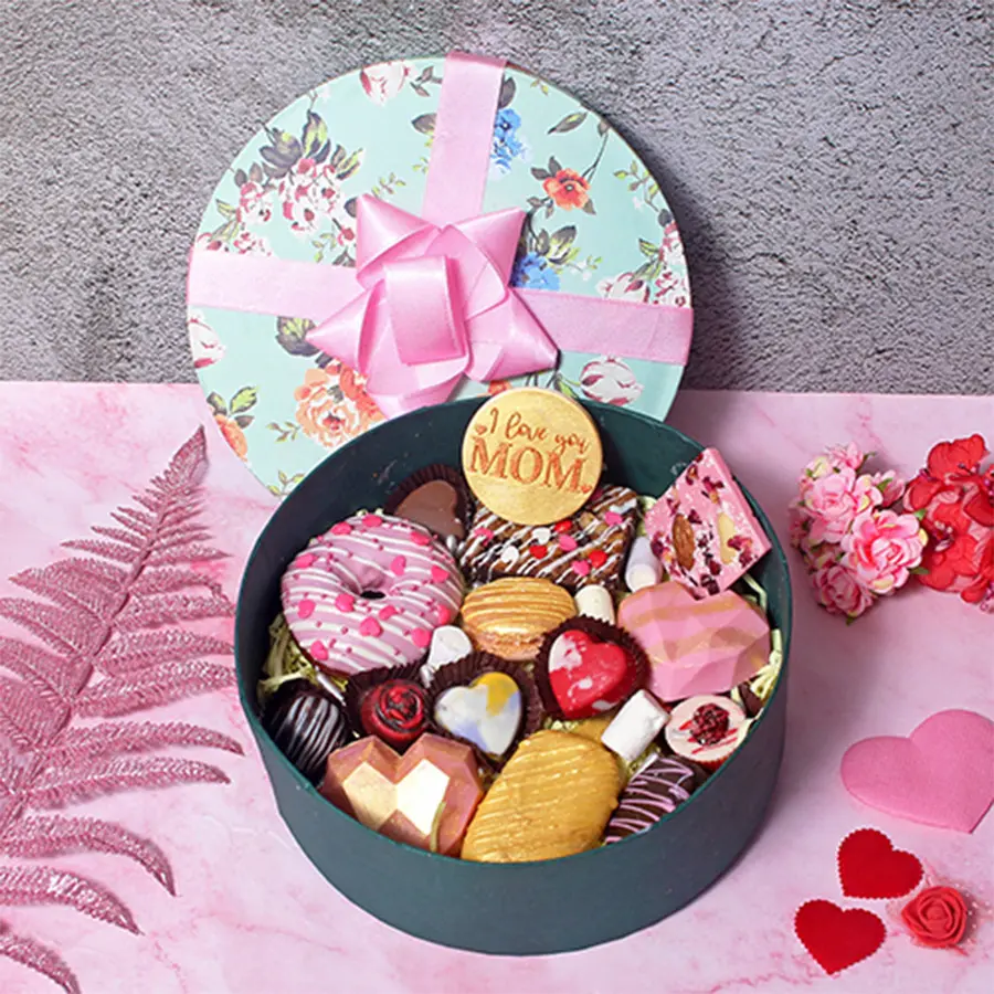 Delightful Chocolaty Magic Mother's Day Hamper featuring a variety of chocolates, a chocolate donut, mini piñatas, a small bar, a walnut brownie, a macaron, assorted chocolates, and chocolate cakesickles.