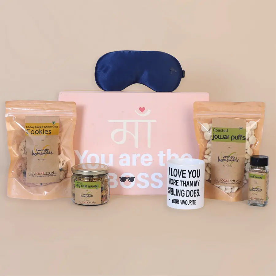 Delightful Wellness Gift Box for Mom featuring an elegant mug, soft eye mask, oats & almond cookies, choco chip cookies, premium dry fruit muesli, aromatic chai masala, and crispy roasted jowar puffs arranged thoughtfully in a beautiful presentation.
