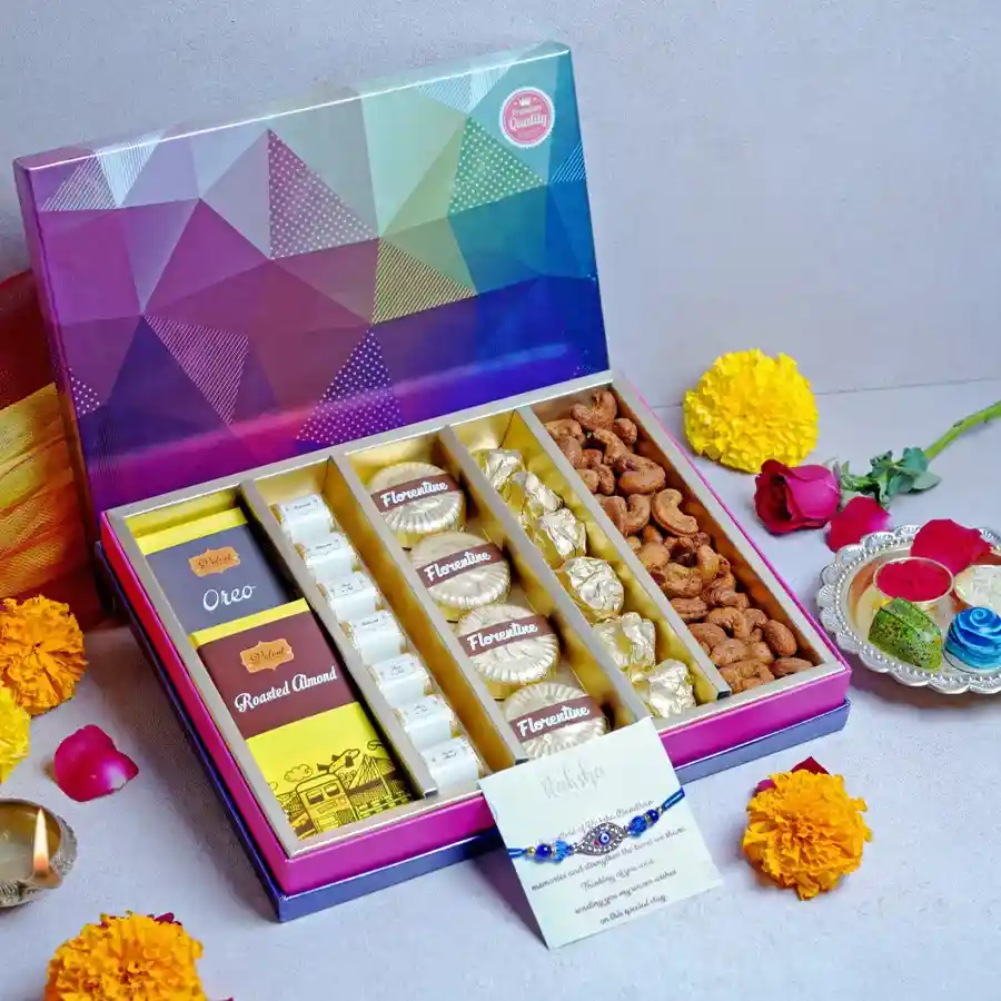 Premium Confections Box featuring Oreo and Roasted Almond chocolate bars, assorted chocolates, Chocolate Almond Florentines, Chocolate Almond Rocks, Cajun Cashews, a designer Rakhi, and a greeting card, all presented in a vibrant multicolored box.
