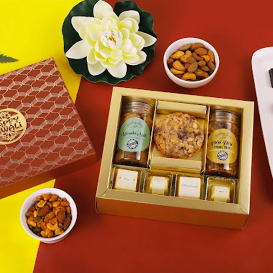 Assorted festive treats in a beautifully decorated box, including chocolates, nuts, trail mix, and a Florentine cookie.