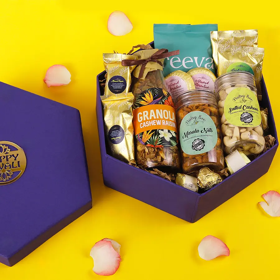 Savory N Sweet Snack Collection featuring almond chocolate fingers, cashew raisins granola, spicy masala nuts, salted cashews, chocochips cookies, almond florentines, assorted chocolates, and almond chocolate rocks in an elegant hamper.