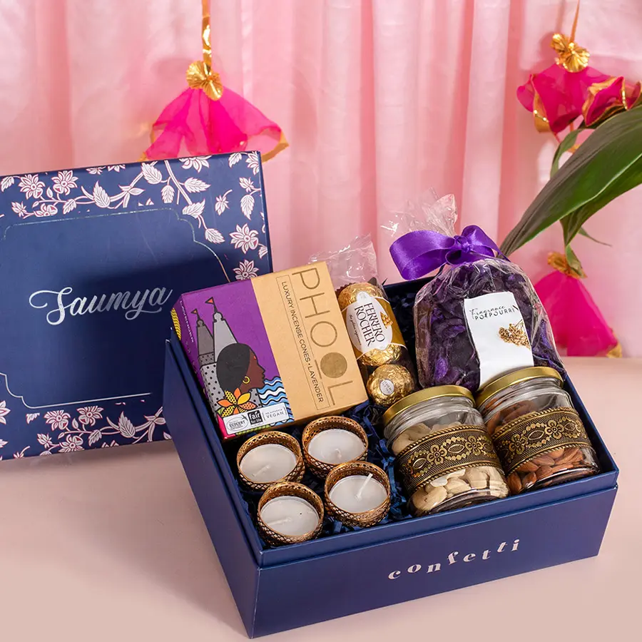 Festive Potpourri and Treats Box with lavender incense cones, Ferrero Rocher chocolates, T-light holders, purple potpourri, glass jars of gold-accented almonds and cashews, all in a personalized blue botanical box.