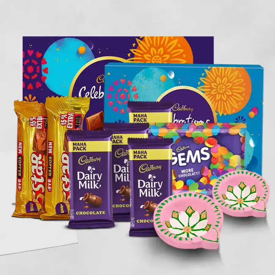 Gift box featuring an assortment of Cadbury chocolates, including Celebrations, Dairy Milk, 5 Star, and Gems, alongside two handmade clay diyas, all set against a festive background for Diwali.