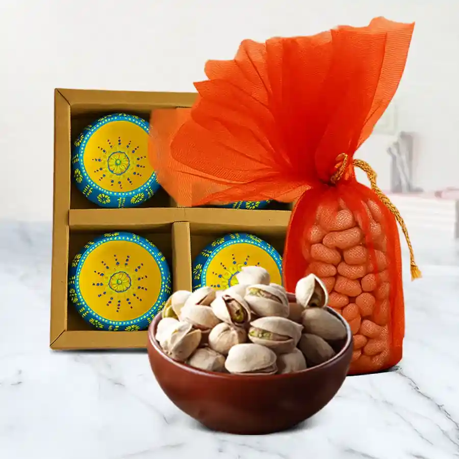 Diwali Illuminate N Indulge Hamper featuring premium pistachios in a net potli and four clay diyas placed together for festive celebration.