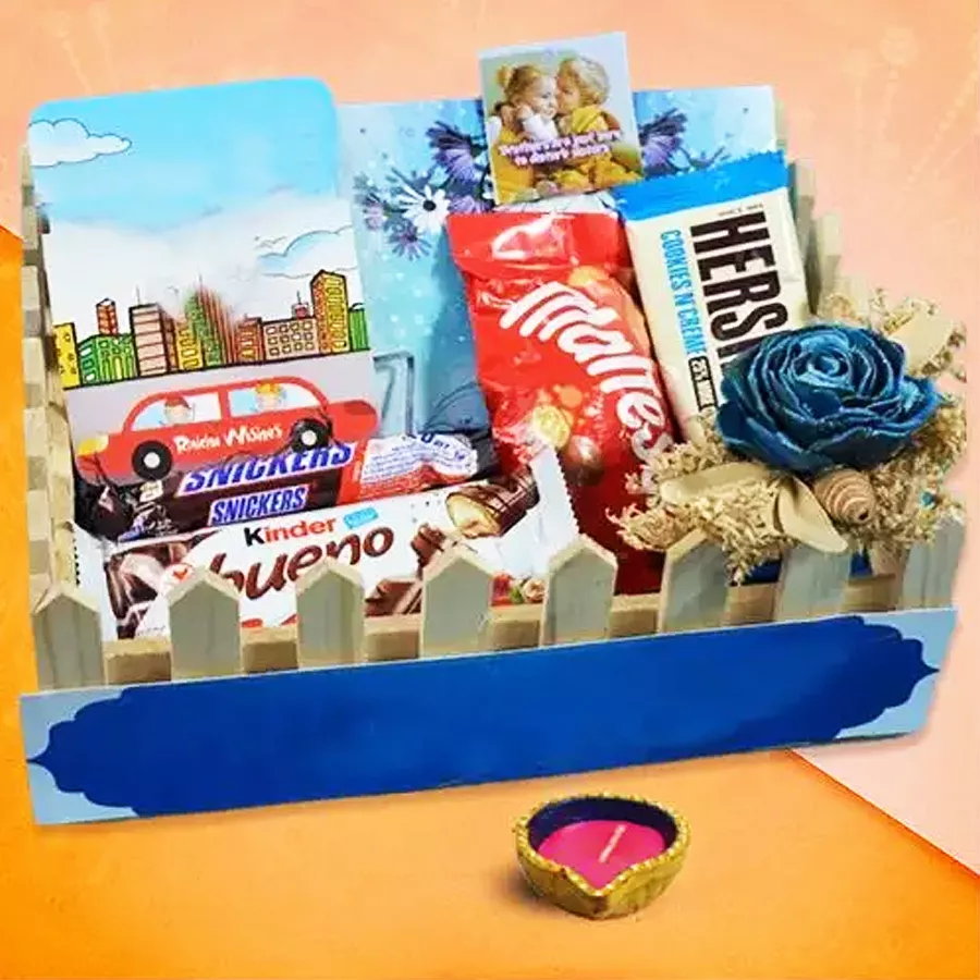Diwali Sweets Diya And Treats hamper featuring a decorative Diya and an assortment of chocolates and candies including Snickers, Kinder Bueno, Maltesers, and Hershey’s Cookies and Cream.