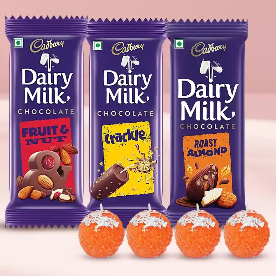 A beautifully arranged hamper featuring three Cadbury Dairy Milk chocolates and four Ladoo-shaped candles, perfect for celebrations.