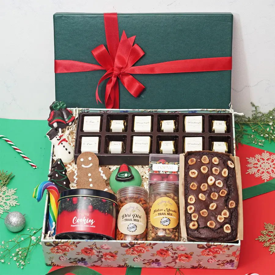 Santa Sweet Treat Gift Box filled with assorted chocolates, a chocolate snowman, festive lollipops, a gingerbread man cookie, a hot chocolate bomb, Nutella hazelnut tea cake, cranberry dragees, trail mixes, cookies in a tin, and a candy cane.