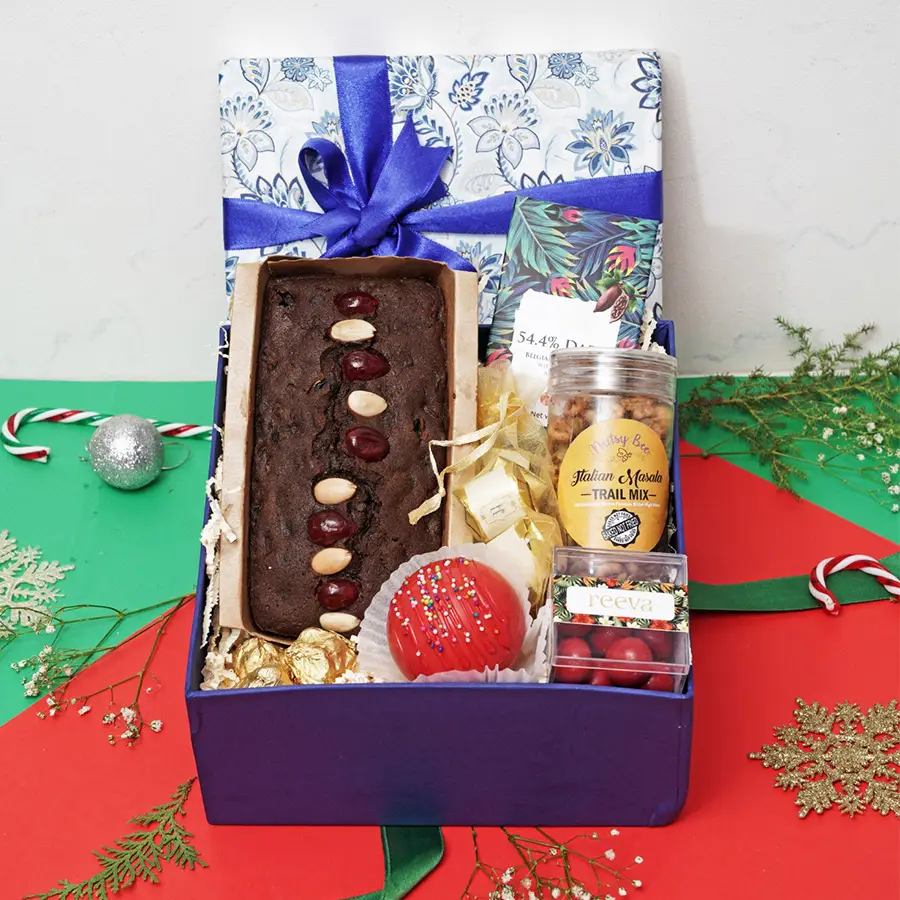 Luxurious Xmas Treats Collection featuring plum cake, almond chocolate rocks, hot chocolate bomb, cranberry dragees, Italian masala trail mix, handcrafted chocolates, and dark Belgian chocolate with almonds