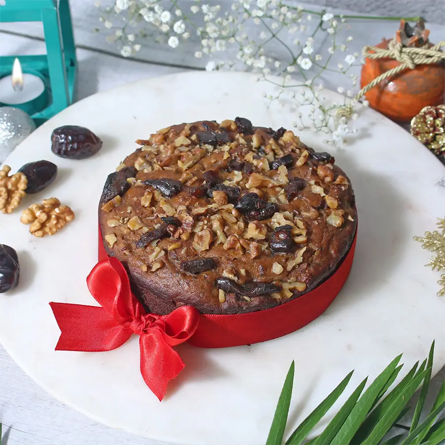 Magical Sugarfree Date and Walnut Cake garnished with walnuts on a wooden table