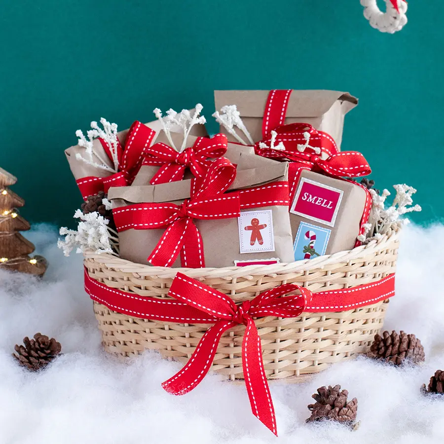 Basket filled with an amber-wood scented candle, a 5x5 photo frame, a wooden mobile sound amplifier, an assortment of homemade cookies, cozy socks, and an eco-friendly cane basket.