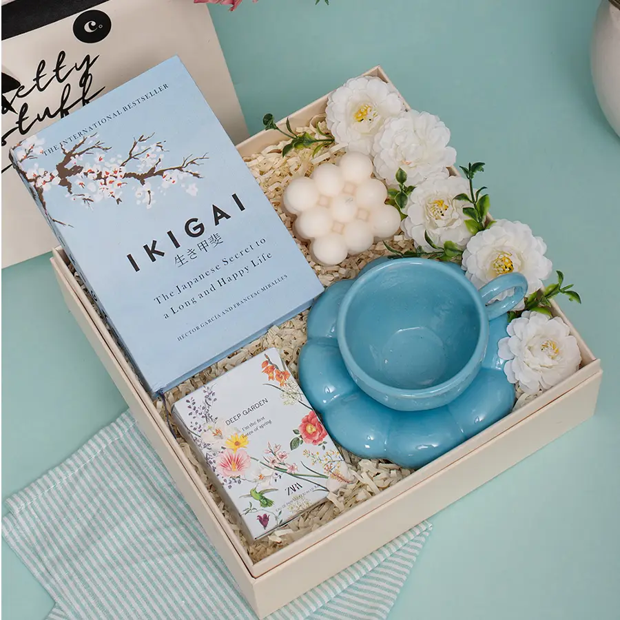 Enchanting Moments Gift Box with Blue Bubble Cup and Saucer, Ikigai Book, White Bubble Candle, Zara Woman Perfume, and fresh flower arrangement in a reusable MDF box.