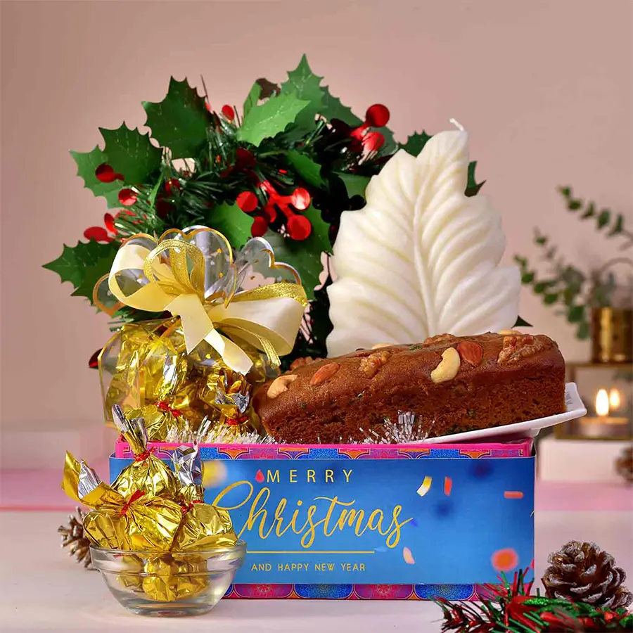 Scented Serenity and Sweet Indulgence Hamper featuring a white designer candle, homemade chocolates, a Christmas wreath, a plum cake, and an elegant serving tray.