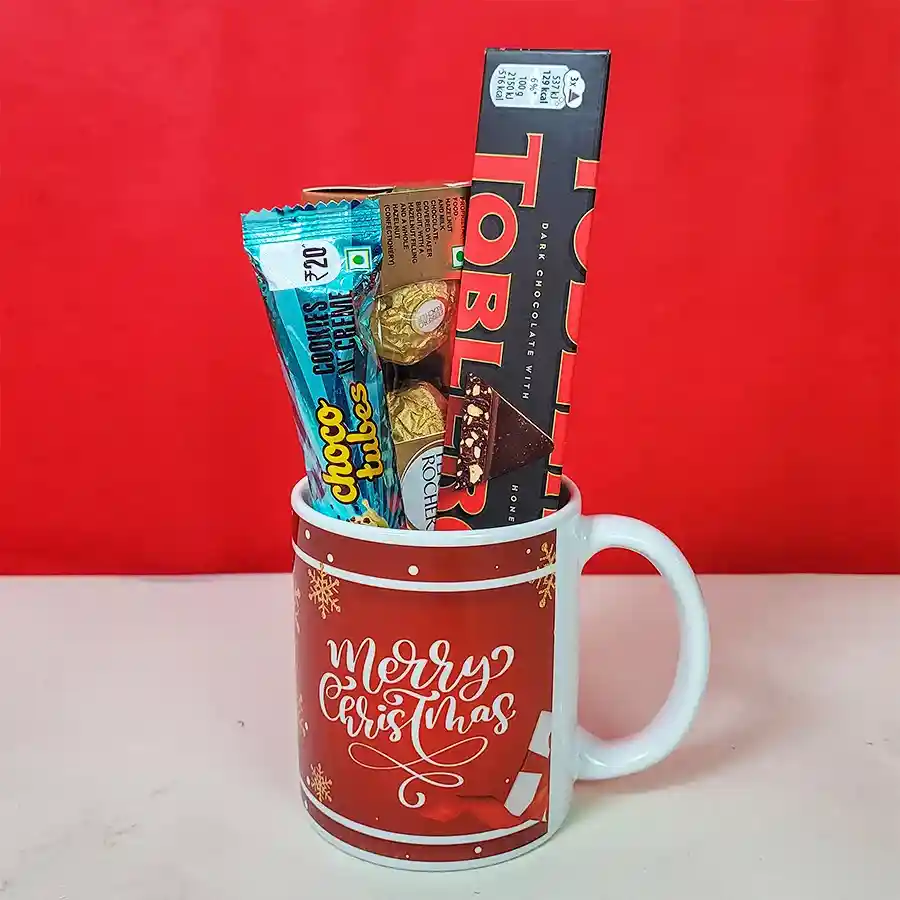 Christmas Mug and Chocolates Elegance Hamper featuring a festive mug, Toblerone dark chocolate bar, Ferrero Rocher chocolates, and Cookies N Crème Choco Tubes.
