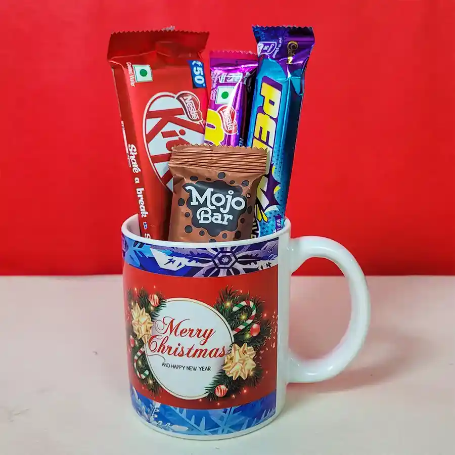 Classic Christmas mug with festive design alongside an assortment of chocolates including Nestle Kit Kat, Nestle Munch, Cadbury Perk, and Mojo Bar