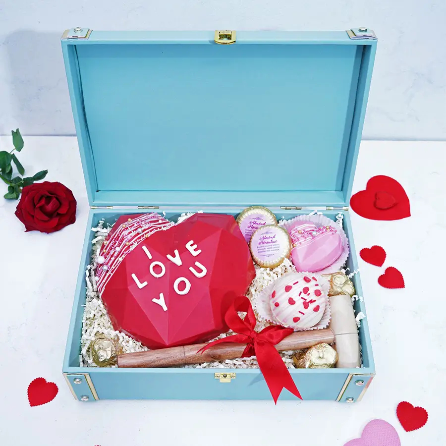 Heartwarming Chocolaty Surprise Box filled with assorted chocolates including a pinata, Almond Florentines, Chocolate Almond Rocks, a Hot Chocolate Bomb, and a heart-shaped chocolate.