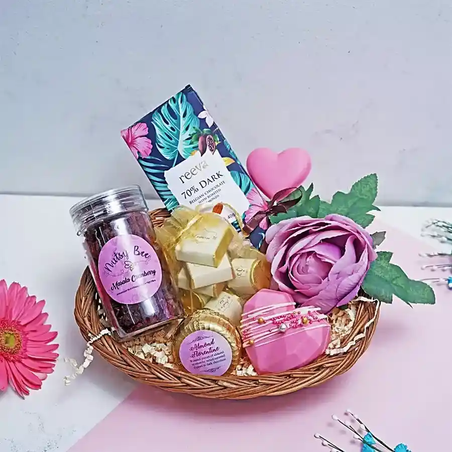Exquisite Chocolate and Cranberry Gift Basket featuring dark chocolate bars, heart-shaped lollipops, hot chocolate piñata, almond florentines, assorted chocolates, and masala cranberry bottle.