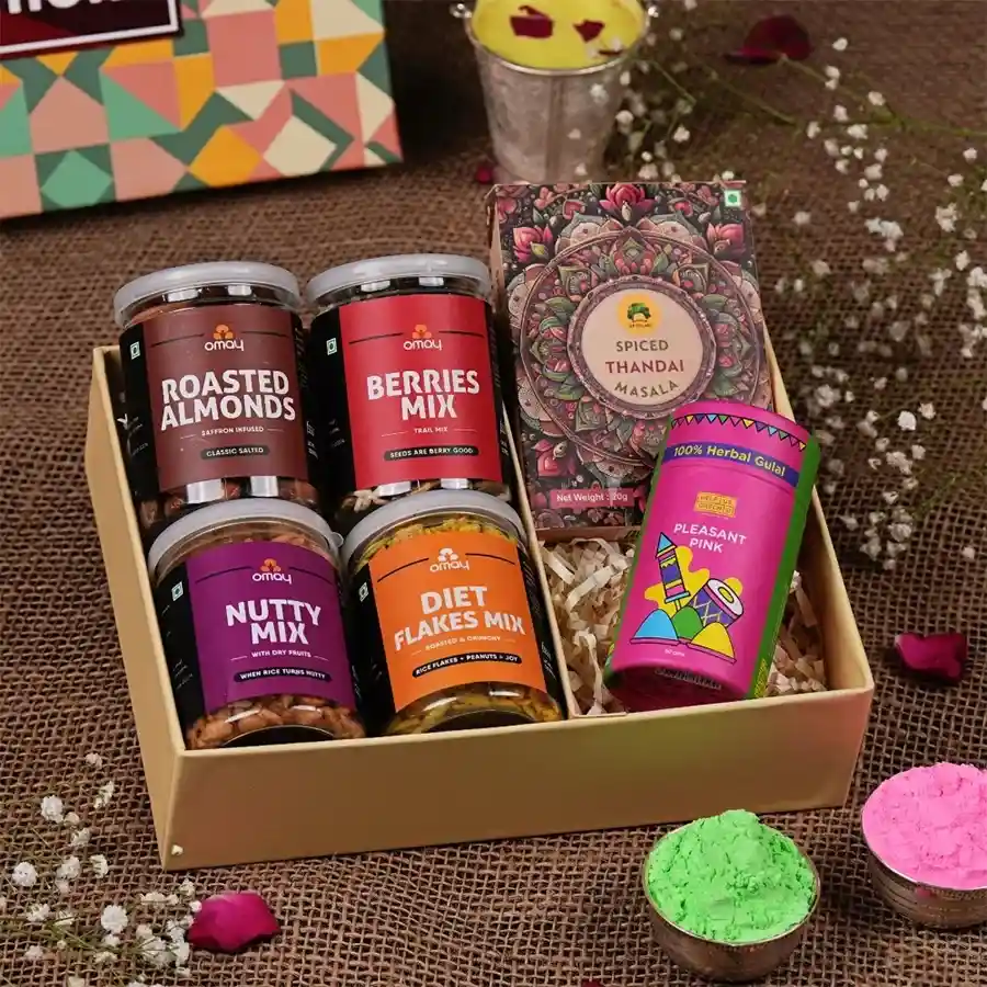 A beautifully arranged gift box filled with salted roasted almonds, a nutty dry fruit mix, diet flakes, sweet berries blend, Gulab's instant Thandai, and herbal Gulaal, accompanied by a vibrant Holi greeting card.