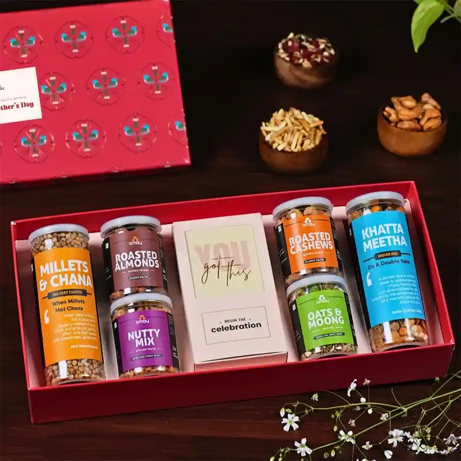 Wholesome Mother's Day Indulgence Gift Box featuring gold foil packaging filled with Khatta Meetha, roasted almonds and cashews, oats, moong, millets, chana, nutty dry fruit mix, Loykas Chocolate Almond Brittle, a pocket diary, and a greeting card.