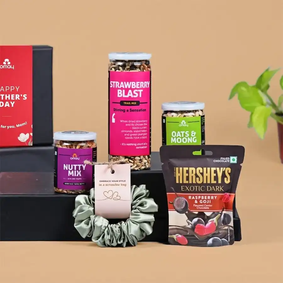 Luxurious Mother's Day treat box containing Strawberry Blast, Oats N Moong mix, Nutty Mix, Hershey's Exotic Dark Chocolates, a satin scrunchie, and a greeting card, elegantly arranged.