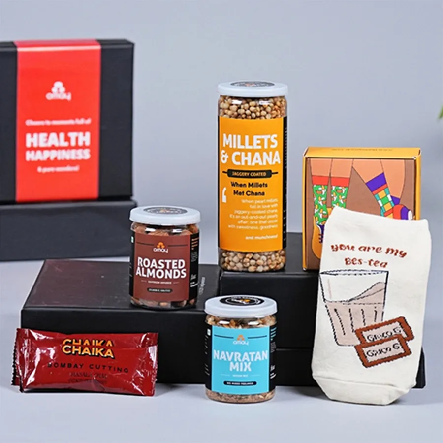 A beautifully arranged gift hamper featuring roasted almonds, Millets N Chana, Navratan Mix, premium Chaikas tea sachets, colorful Tea Lover socks, and a Father's Day card, all presented for a tea-loving dad.