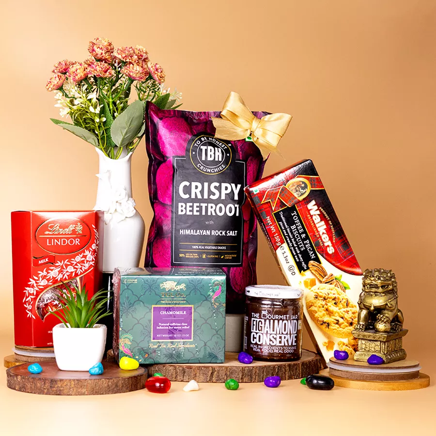 Gourmet Indulgence Gift Hamper featuring Lindt Lindor chocolates, Tbh Crispy Beetroot Chips, Fig Almond Conserve, Tgl Chamomile Tea, and Walkers Toffee Pecan Biscuits arranged in a beautiful basket.