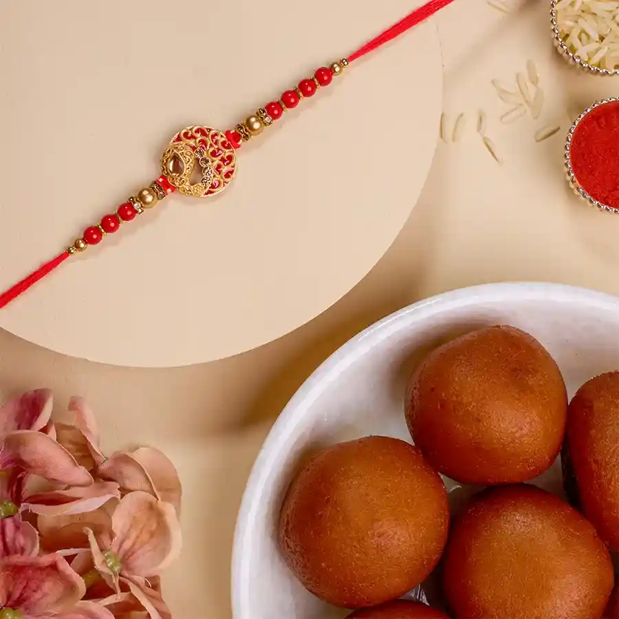 Festive Kundan Rakhi set with intricate designs, 500g of Gulab Jamun, Roli, Tika, Chawal, and a personalized message card
