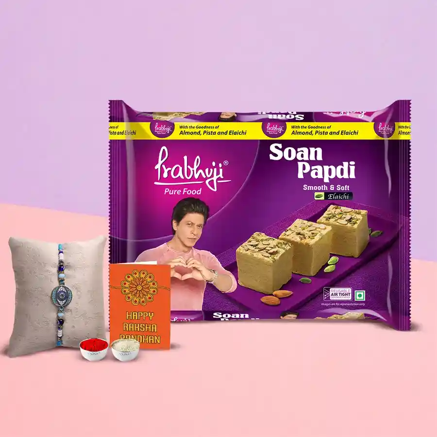 Haldiram's Soan Papdi and Rakhi gift set with 200g of Soan Papdi, a vibrant Rakhi, Roli Tilak, and Chawal against a decorative background.