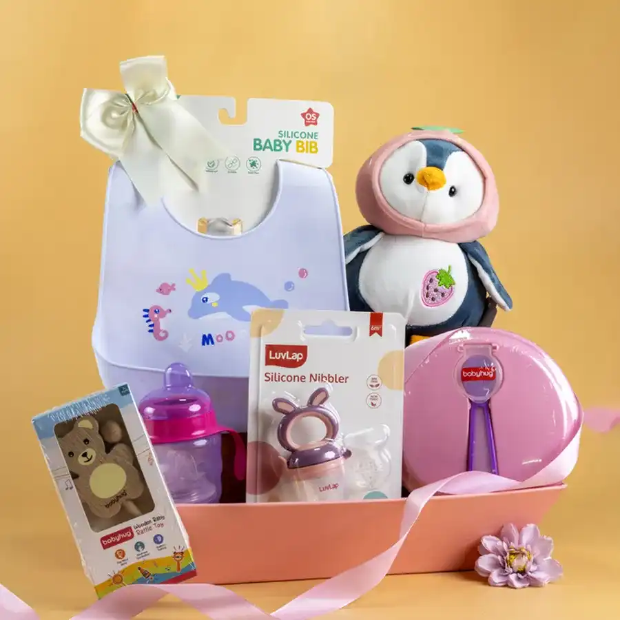Premium Baby Feeding & Fun Hamper featuring a silicone bib, wooden rattle, feeding bowl and spoon set, blue sipper cup, Luvlap nibbler, and a Baby Penguin soft toy in a reusable designer basket.