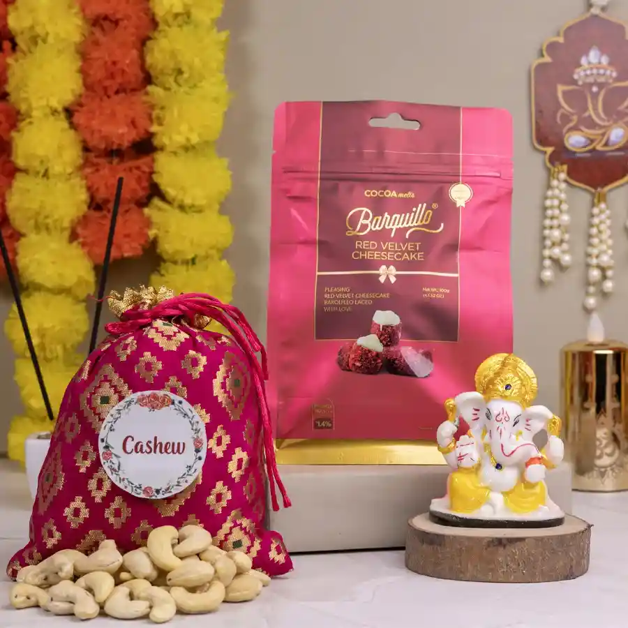 Divine Mukut Ganesh statue alongside gourmet goodies including 100g Almond Potli and 100g Barquillo Red Velvet Cheesecake in an elegant gift set.