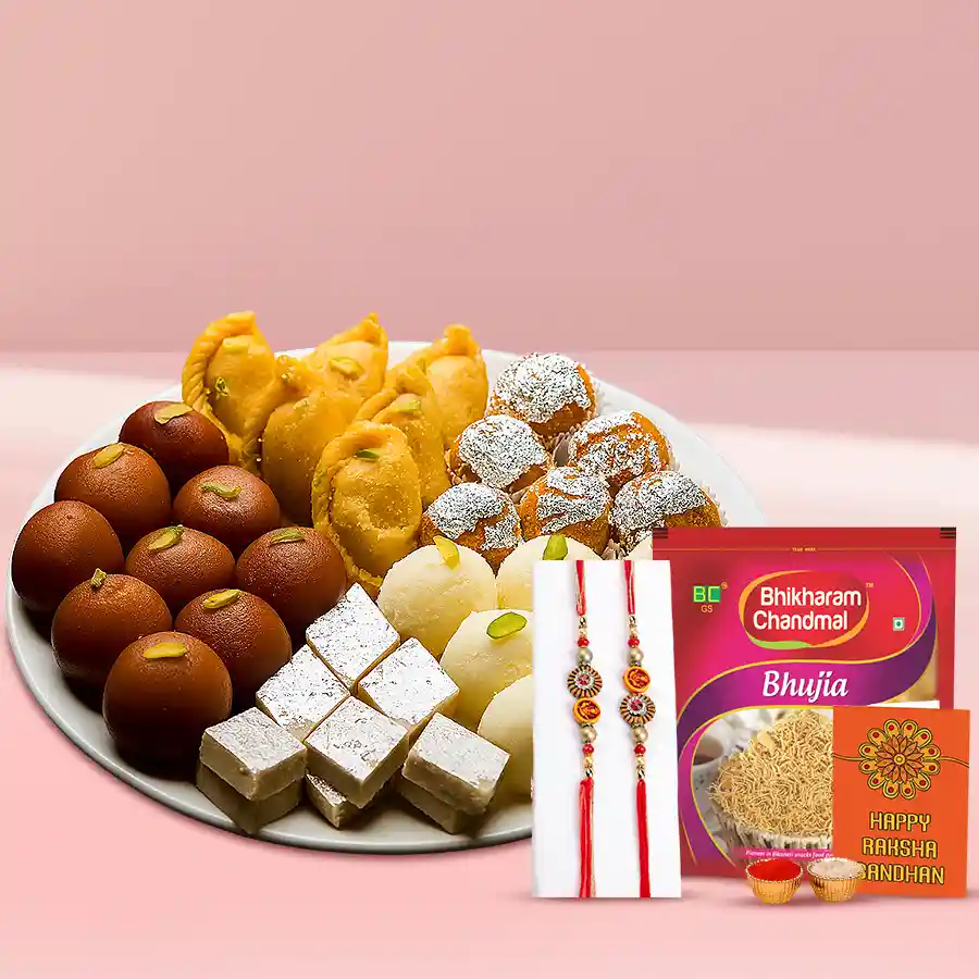 Delightful Rakhi pair with assorted mithai and crunchy bhujia, including roli, tika, chawal, and a personalized card.