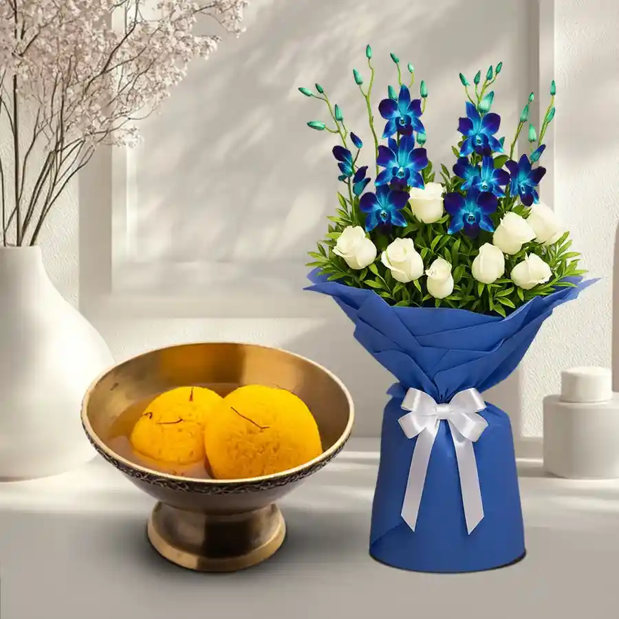 Stunning blue orchid and white rose bouquet with Raj Bhog sweets in an elegant gift combo.